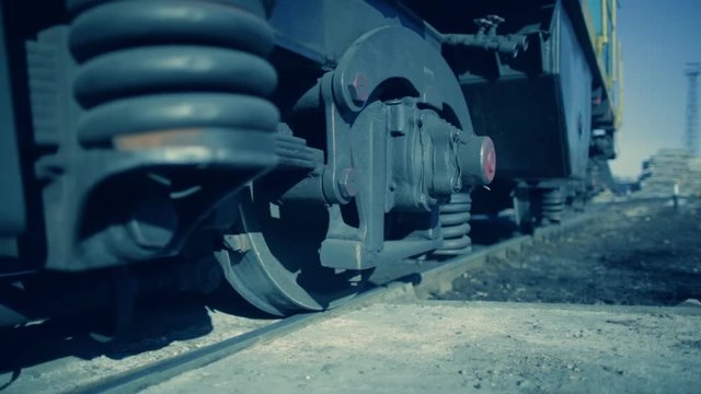 Powerful black metal wheels and springs near a stopped railway train. Bottom view, from rail