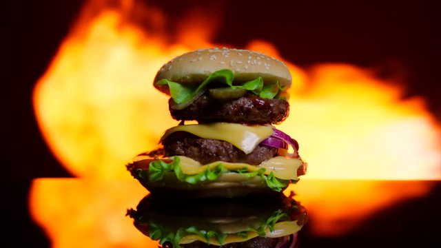Delicious burger is on fire on the black mirror surface