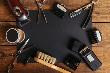 Top view of various professional barber tools on black card on wooden surface - Powered by Adobe