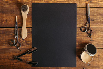 top view of professional barber tools and blank black card on wooden table