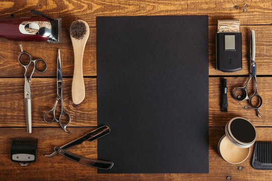 top view of professional barber tools and blank black card on wooden table
