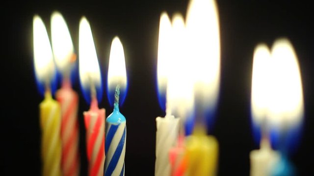 Macro of various colorful birthday candles slowly burning down.