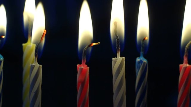 Macro of various colorful birthday candles slowly burning down.