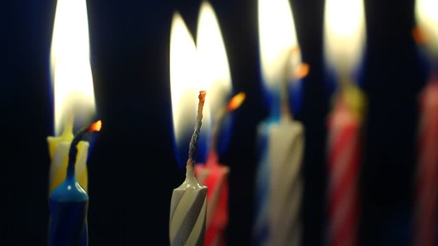 Macro of various colorful birthday candles slowly burning down.