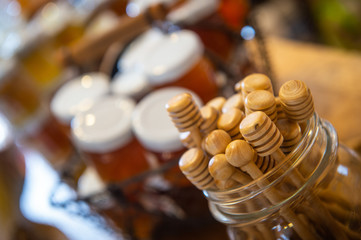 Jars and honey sticks with natural honey on shelf in shop. Sale of natural honey in market