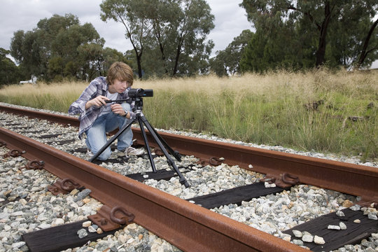 A Teen Making A Film Shooting Outdoors Using Video Camera And Tripod.