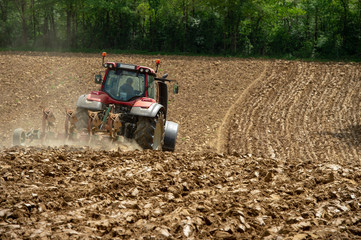 Farmer on tractor plow field, France