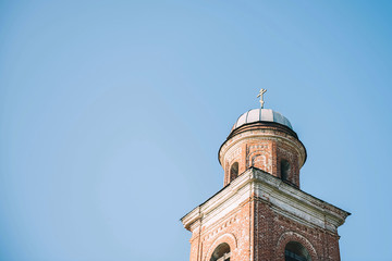  The bell tower of the old church in the small town. Against a blue sky.