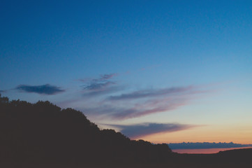 Picturesque evening sky after sunset over dark dense forests