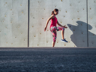 fitness lady making balance Pose outdoor infront of a grey cement wall as background