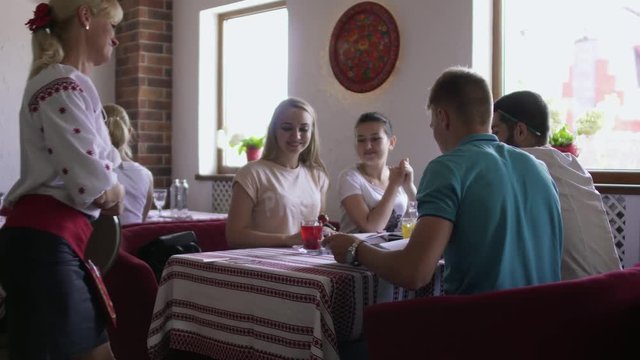 Waitress bring drinks to studying students in cafe