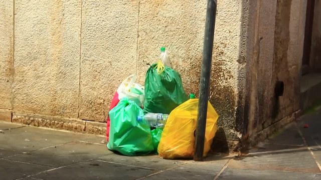Various colorful and full trash bags on the street, waiting for transport.