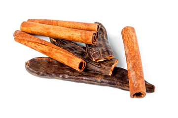 Fruit and carob tree seeds and cinnamon sticks shot close-up on a white background