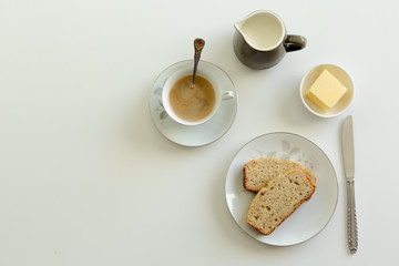 Afternoon tea setting on a white background with banana cake and butter