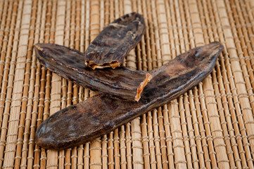 Fruits and carob seeds taken close-up against the background of a bamboo mat