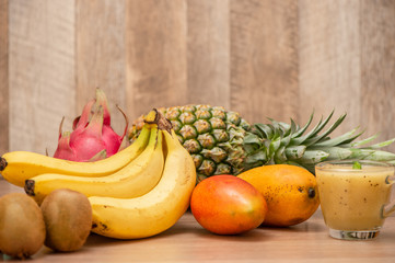 Tropical fresh fruit set and juice smoothies isolated with wooden background