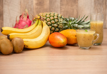 Tropical fresh fruit set and juice smoothies isolated with wooden background