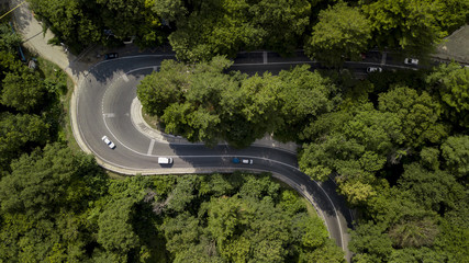 Aerial stock photo of car driving along the winding mountain pass road through the forest in Sochi, Russia. People traveling, road trip on curvy road through beautiful countryside scenery.