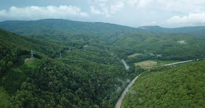 4K aerial stock footage of car driving along the winding mountain pass road through the forest in Sochi, Russia. People traveling, road trip on curvy road through beautiful countryside scenery.