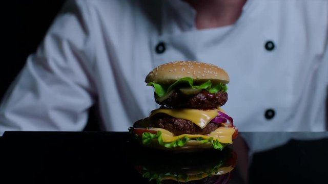 Chef is cooking burger. Black background