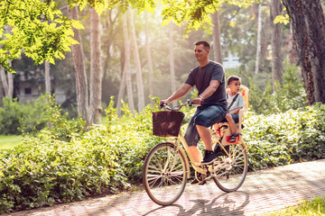 Happy family. Father and son riding bike in the park.