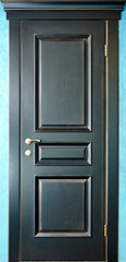 Wooden interior black and golden door of ebony with brass metal handle on blue