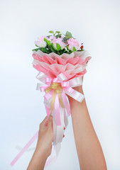 Woman hands holding artificial pink roses bouquet isolated on white background.