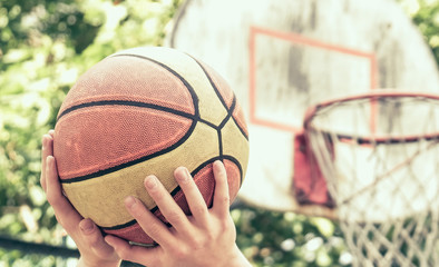 Fototapeta premium Scoring basket in basketball court. Handsome male playing basketball outdoor. Toned.