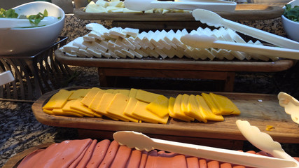 Point of view, the camera looks at rows of fresh cheese of different varieties, sauces and vegetables. Cheese as the main snack at breakfast in the buffet restaurant.