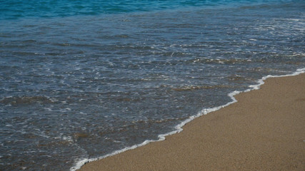 Sandy beach and soft wave of blue ocean. Hot summer day and sandy beach background.