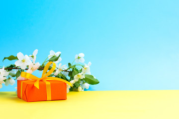 Gift orange box  yellow bow white flowers green desk background