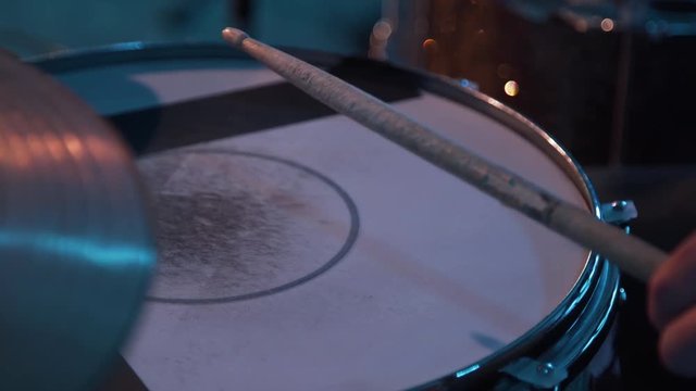 Close-up of drummer doing a trill on a worn snare drum head with wooden pair of drumsticks