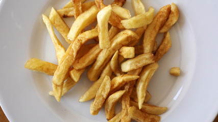 Fried potatoes, French chips are spinning on a plate.