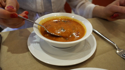 The girl is eating soup. Shooting close-up of a plate with soup.