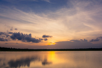 Sunset in the lake. beautiful sunset behind the clouds above the over lake landscape background