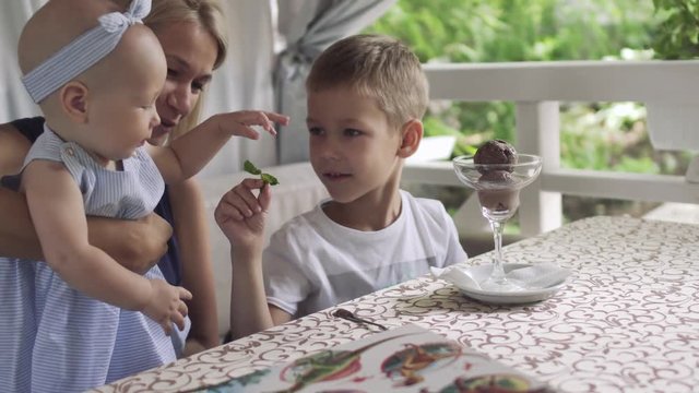 Little boy plays with his baby sister at the table