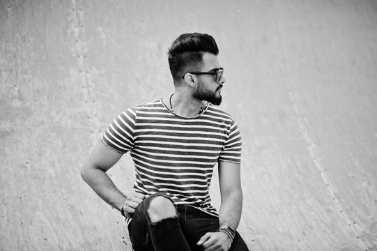 Handsome tall arabian beard man model at stripped shirt posed outdoor. Fashionable arab guy at sunglasses.