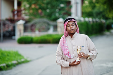 Middle Eastern arab business man posed on street with golden cup at hands.