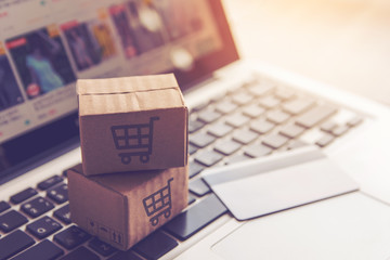 Shopping online. Cardboard box or parcel with a shopping cart logo in a trolley on a laptop...