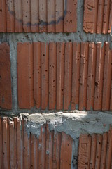 Stylish corrugated red clay bricks, brickwork with gray cement as construction work of builders
