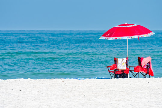 Beach umbrella, chairs, white sand and aquamarine water 