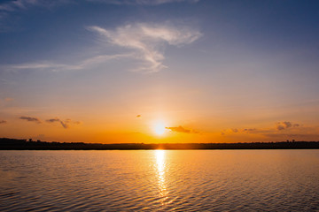 Fototapeta premium Sunset in the lake. beautiful sunset behind the clouds above the over lake landscape background. dramatic sky with cloud at sunset