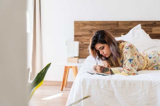 Pretty female drawing on bed
