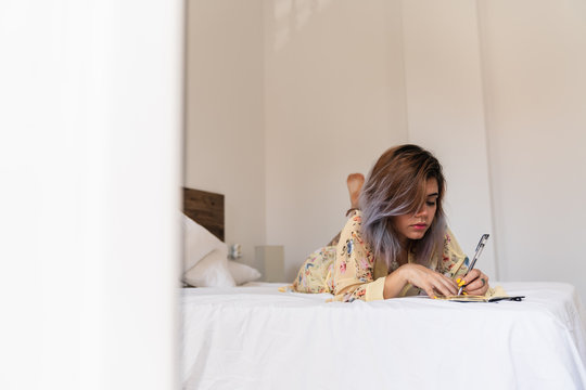 Left handed lady writing and lying on bed