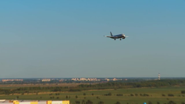 Landing aircraft on the background of the whole Pulkovo airport. We see the airport building, cars of passengers and people meeting, transportation of technical services and a pond