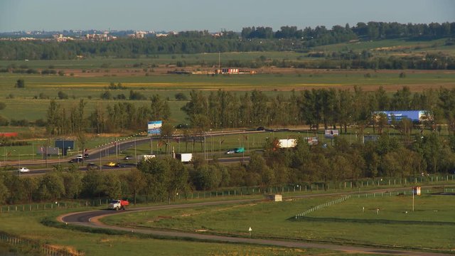 Automobile traffic near Pulkovo airport against the backdrop of beautiful fields, trees and houses