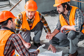 close-up shot of group of confident builders having conversation about building plan