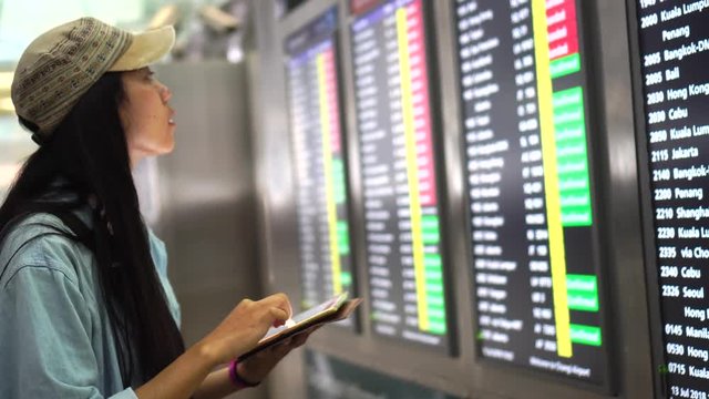 Attractive girl swiping through her tablet computer with the digital board at train station, Singapore : 4k