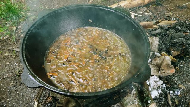 Preparation of uzbek national dish - pilaf in a large cast-iron cauldron on the fire. 4K