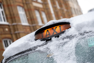 London Taxi in the snow with orange For Hire light glowing